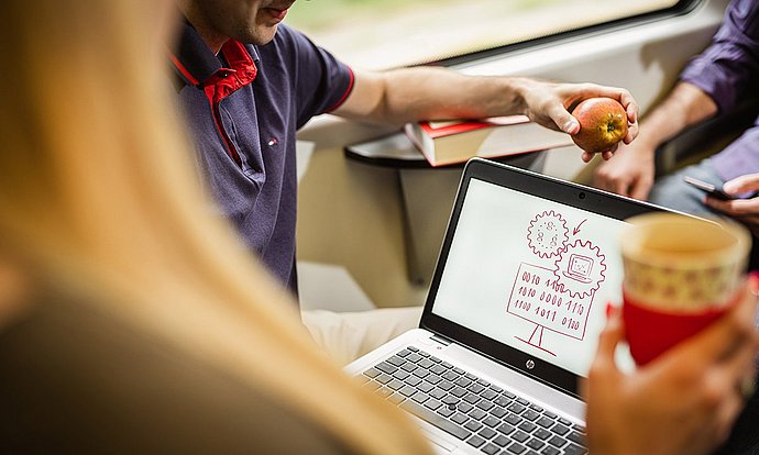 Themen wie Daten-Handling und Mobile Business werden von zwei Studenten im Zug besprochen.