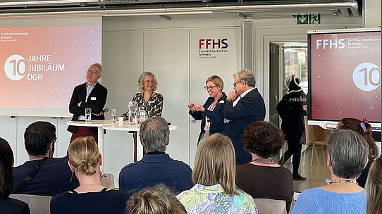 Rednergruppe steht vor Publikum